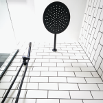 black showerhead and white tiles with black grout