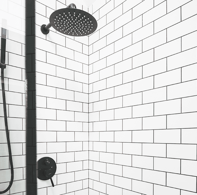 black showerhead and white tiles with black grout