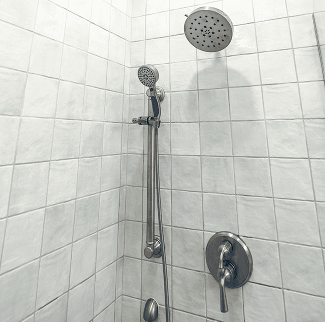 bathroom shower with white tiles and stainless steel shower head