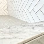 Close-up of herringbone tile pattern with marble countertop.