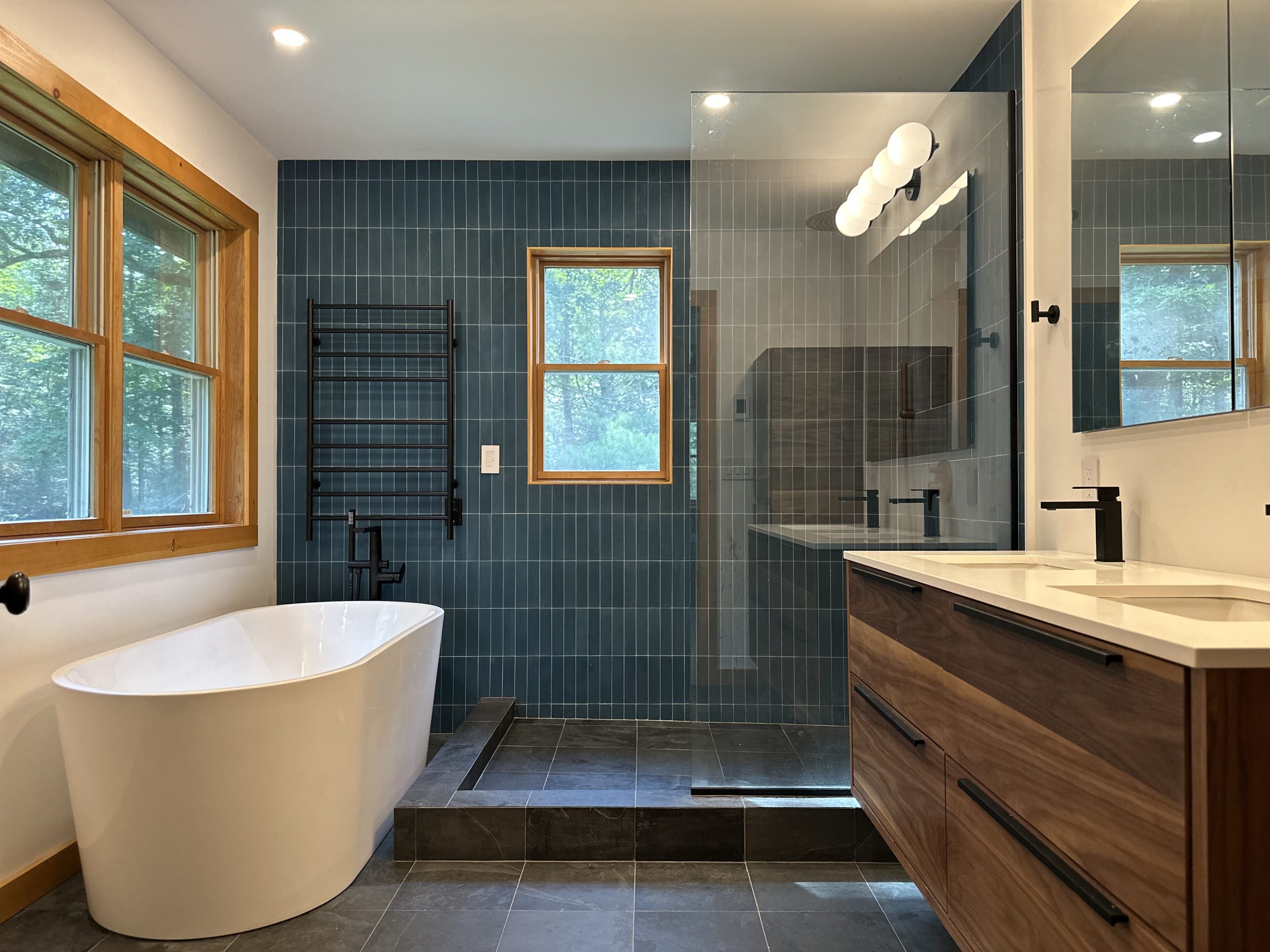 Modern bathroom with a freestanding tub, glass shower, and wood accents, ideal for bathroom renovation, construction, and remodeling services.