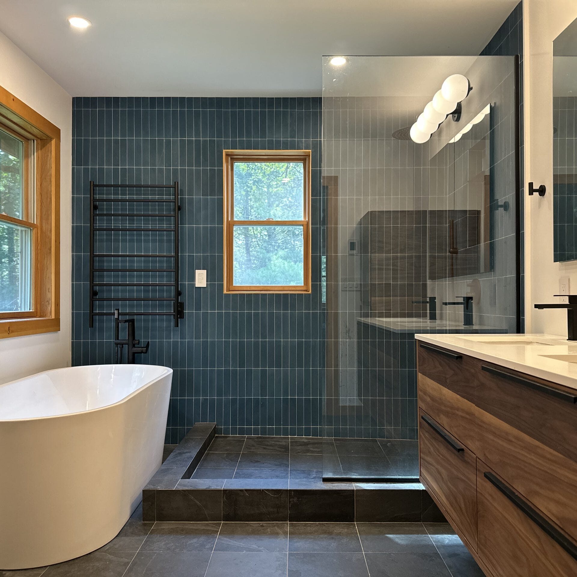 Contemporary Bathroom with Freestanding Tub and Glass Shower Modern bathroom with a freestanding tub, glass shower, and wood accents, ideal for bathroom renovation, construction, and remodeling services.