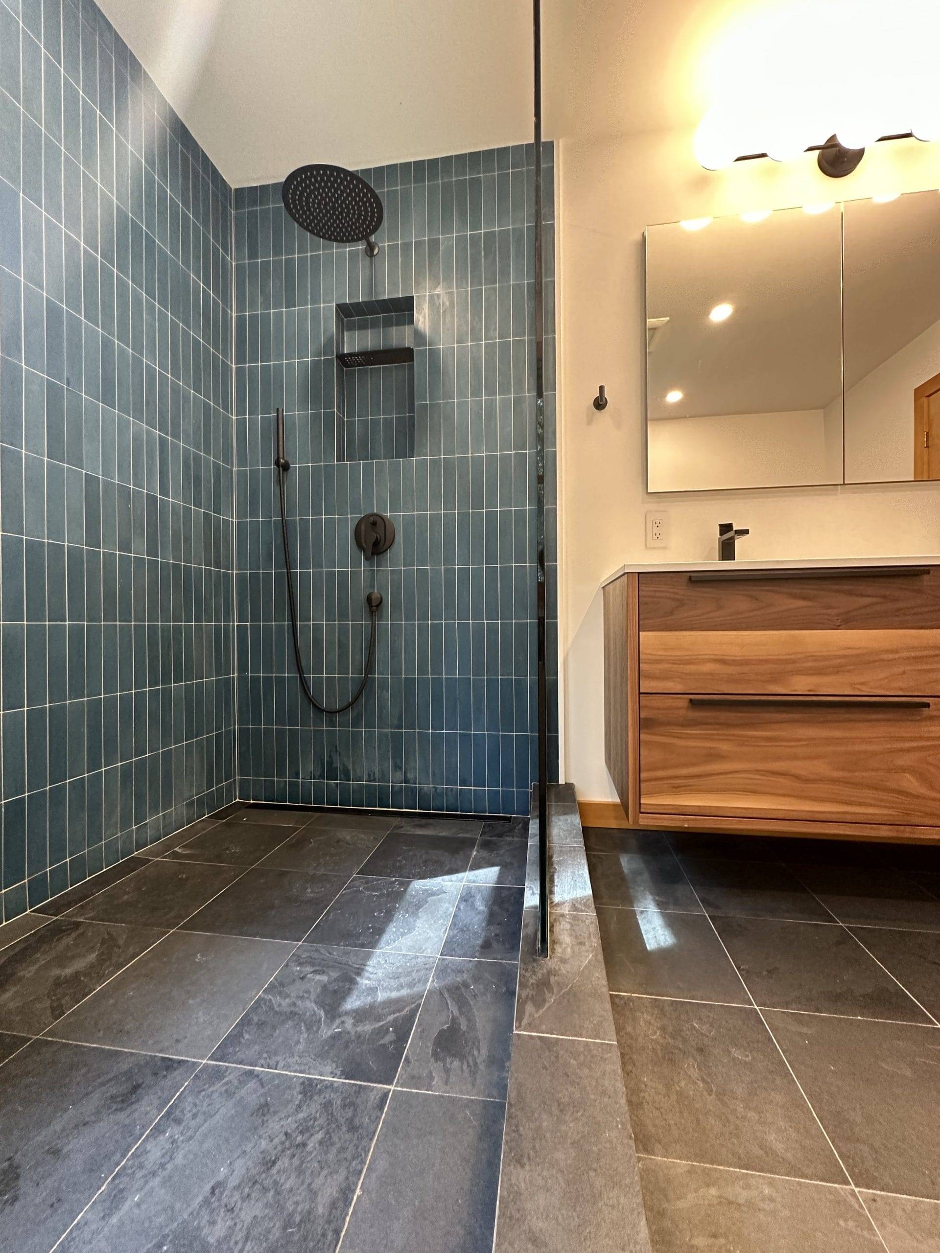 open shower with dark green vertical tiles