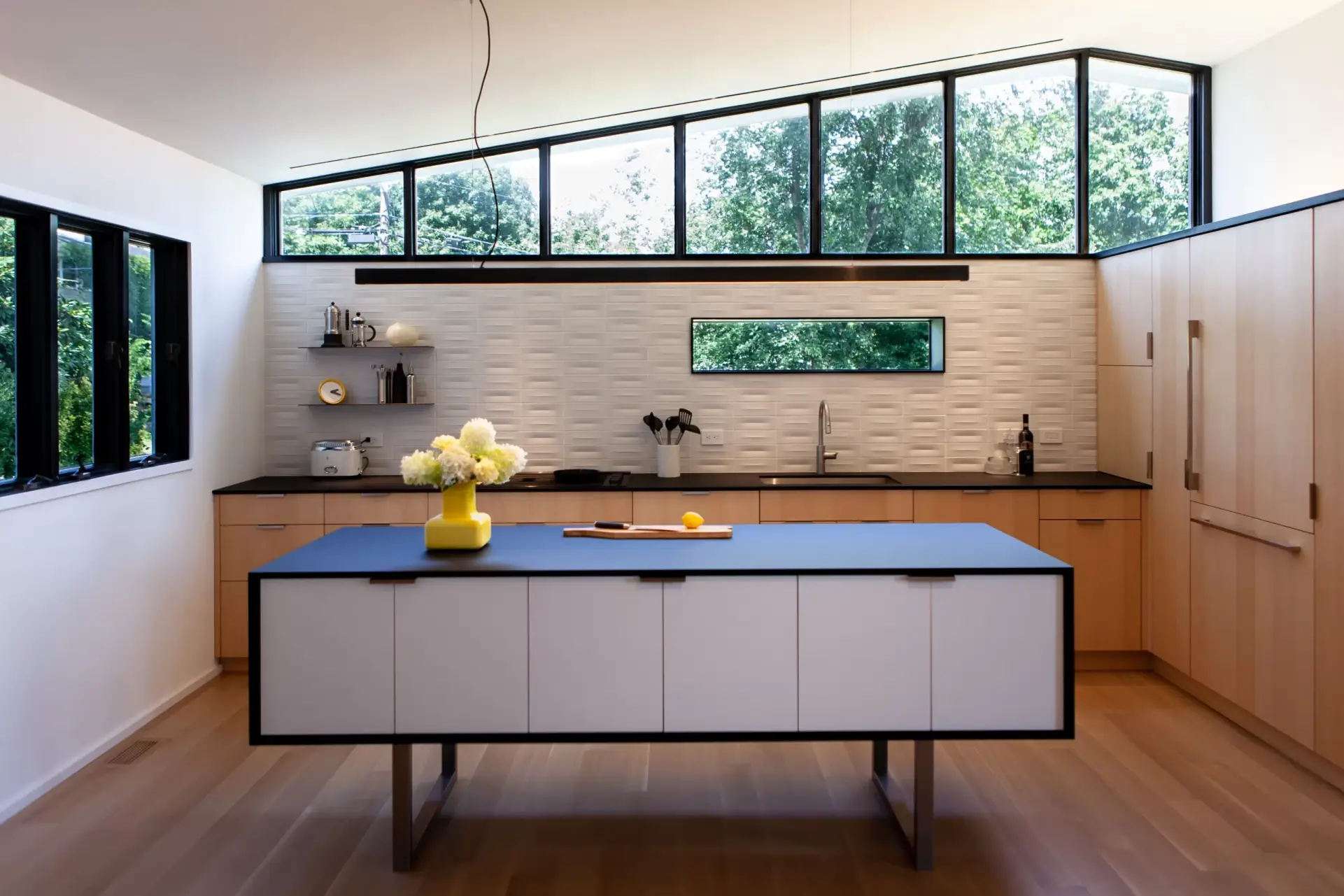 black stained kitchen island in a kitchen with white walls and natural ash stained cabinets